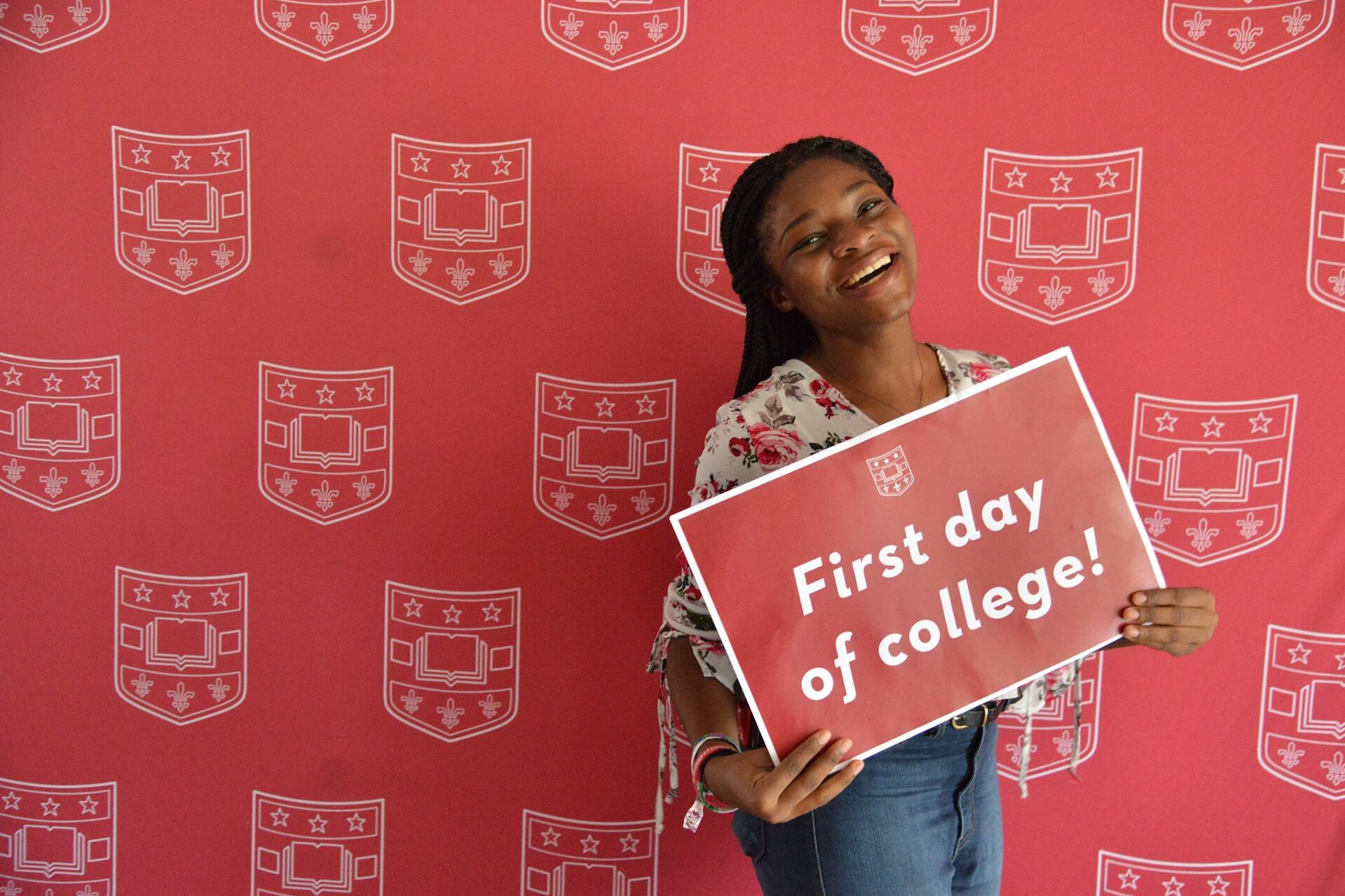 A student poses with a sign on the first day of class